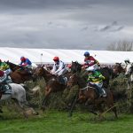 Horses jump a fence in the Grand National 2024 Aintree